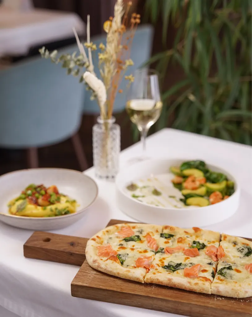 Mesa con flores, pizza y ensalada