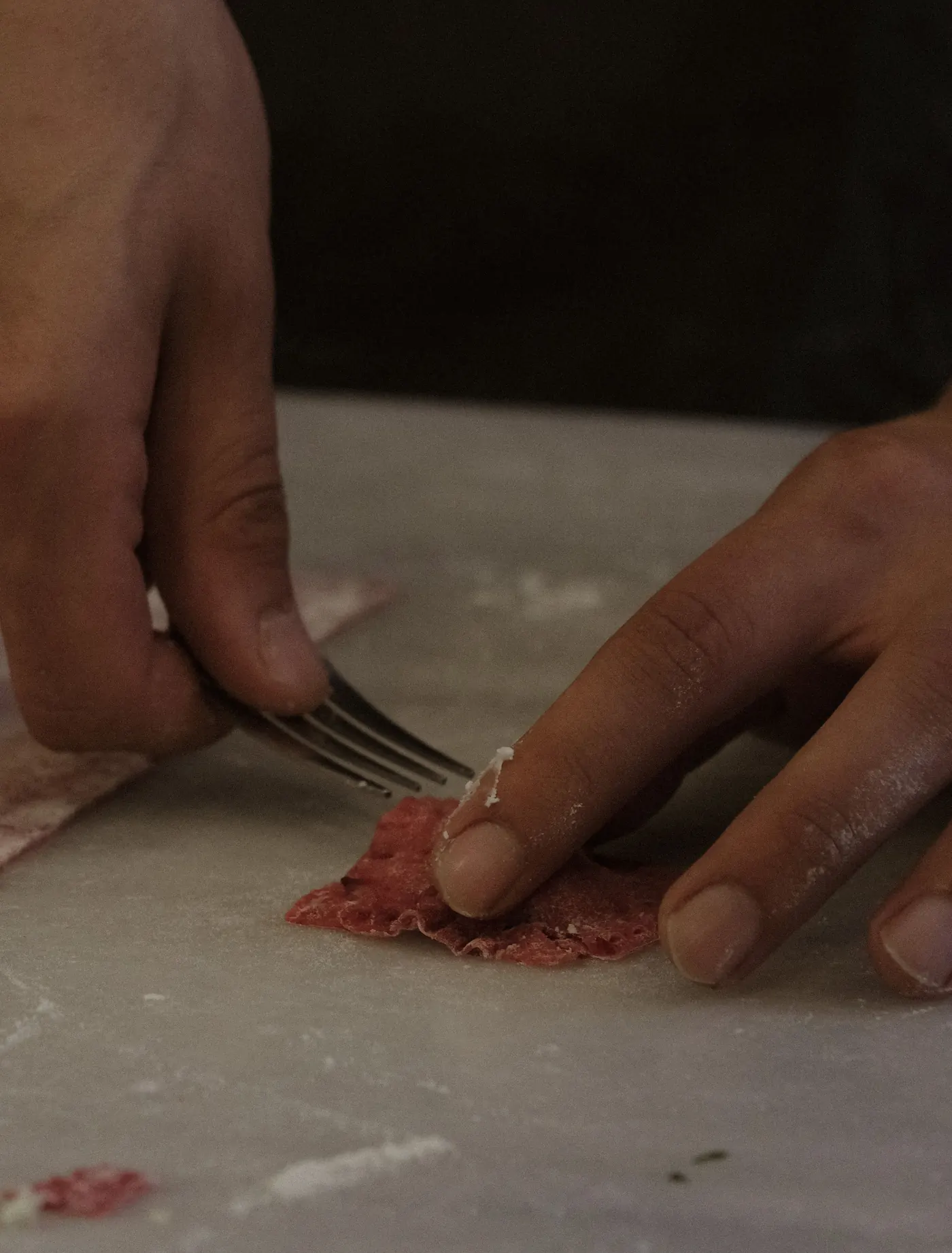 Manos preparando pasta fresca sobre la mesa de trabajo